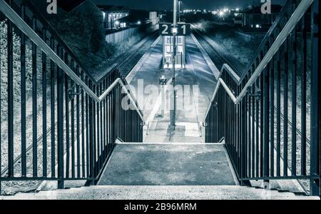 Empty suburban railway station (with no wheelchair access) at night. UK Stock Photo