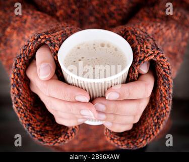 Woman hands in an oversize sweater holding a cup of coffee. Hot drink is best treat from virus disease Stock Photo