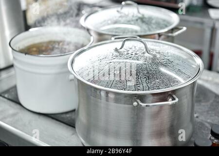 Closeup of large pots on the stove. Chef cooking at commercial kitchen - hot job. real dirty restaurant kitchen. Stock Photo