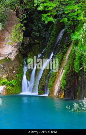 small waterfall among green stones in mountains Stock Photo