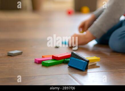 A child plays with colored plasticine for modeling on the wooden floor. Stock Photo
