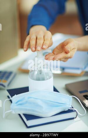 Closeup on woman sanitizes hands with a disinfectant in temporary home office during the coronavirus epidemic at home in sunny day.