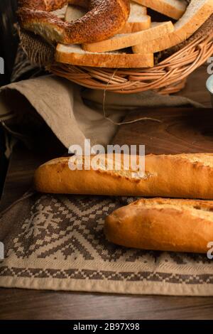 French baguette with slices of bread and bagels in basket Stock Photo