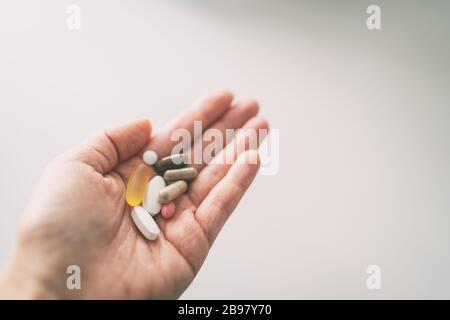 Vitamins, minerals and supplements pill capsules woman taking many pills top view of hand holding tablets Stock Photo