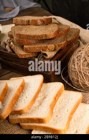 Slices of dark and white bread in box and on tablecloth Stock Photo