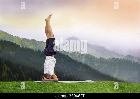 man standing on her head doing yoga in Himalayan mountain Stock Photo