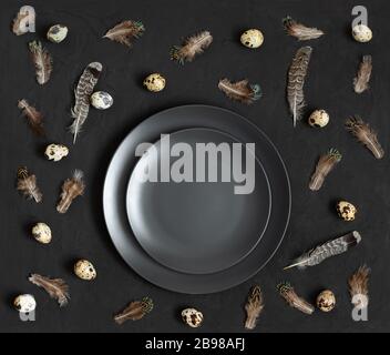 Easter dark table setting with quail eggs in a nest on a black background. Easter pattern. Copy space, top view, flat lay. Stock Photo