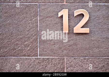 Elegant number 12 / twelve, metal digits on masonry background. Stock Photo