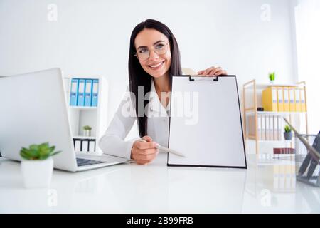 Photo of pretty professional doc lady hold clipboard with hospital contract insurance showing patient place for signature wear white lab coat sit Stock Photo