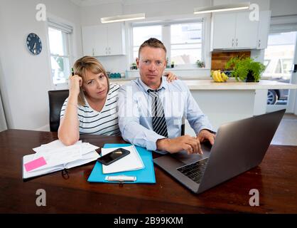 Coronavirus economic recession. Family couple with masks in distress over home finances and small business debts during quarantine and shutdown. impac Stock Photo