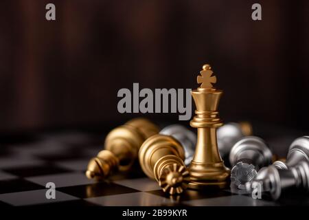 gold king is the winner standing in the midst of falling chess on board in game Stock Photo