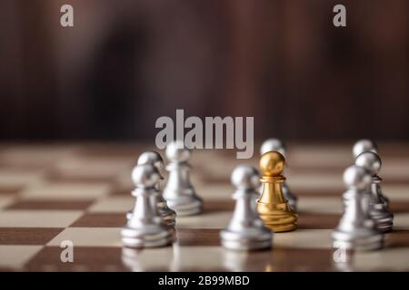 gold chessman standing in the midst on board with wooden background Stock Photo