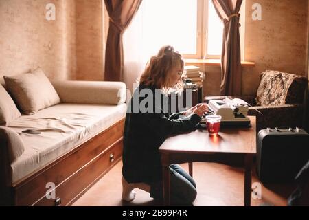 Young female writer using typewriter at home Stock Photo