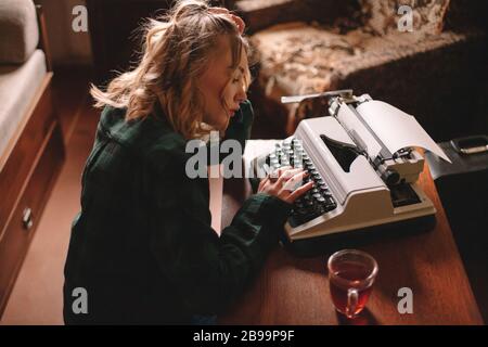 Young female writer using typewriter at home Stock Photo