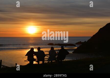 A small group of friends takes in sunset at Indian Beach, Ecola State Park, Oregon coast, USA Stock Photo