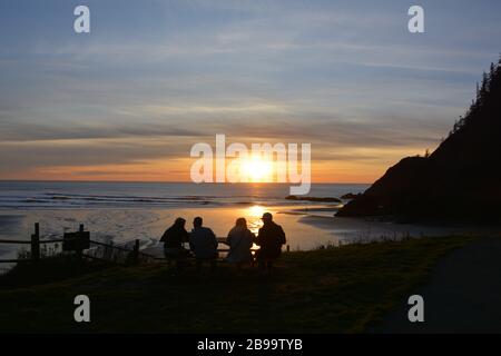 A small group of friends takes in sunset at Indian Beach, Ecola State Park, Oregon coast, USA Stock Photo