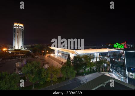 Abai Square, Almaty at night showing the modern Kok Tobe funicular station, Palace of Republic concert hall and Hotel Kazakhstan. Stock Photo