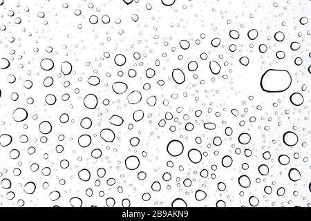 close up of rain drops on a sunroof on a cloudy day from the interior of the car perspective Stock Photo