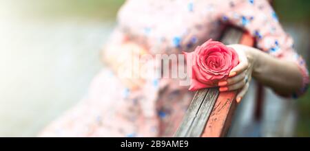 Pregnant woman touching bump whilst holding pink rose girl waiting Stock Photo
