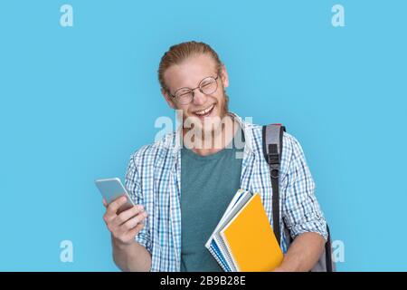 Bearded young man in glasses hold modern smartphone laughing at joke. Stock Photo