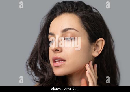 Pretty brunette girl touching her neck and looking calm Stock Photo