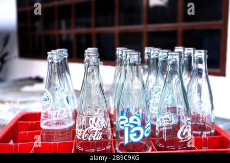 Box with empty glass bottles of Coca Cola, and other drinks. Recycling Glass Bottles. Stock Photo