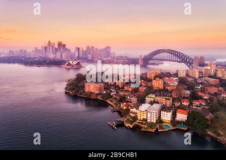 Sydney harbour and major city landmarks of waterfront around Sydney Harbour bridge in aerial view at pink sunrise. Stock Photo