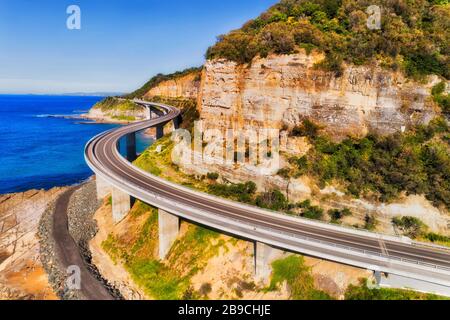 Elevated winding road of Grand Pacific Drive as Sea cliff bridge from Sydney to Wollongong - aerial view on a sunny day. Stock Photo