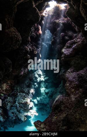 Sunbeams penetrate the cave entrance from above, Red Sea. Stock Photo