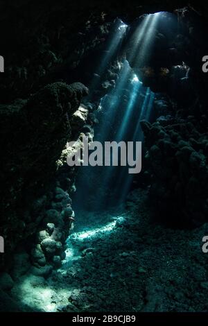 Sunbeams penetrate the cave entrance from above, Red Sea. Stock Photo