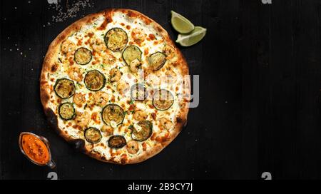 Tasty italian white pizza with seafood made after an authentic recipe. Mozzarella mealted on top. Sauce and lime aside. Stock Photo