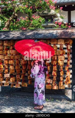 Two Japanese dressed with a yukata and umbrella. Engimono. Ema (Shinto) Wooden boards with wishes Stock Photo