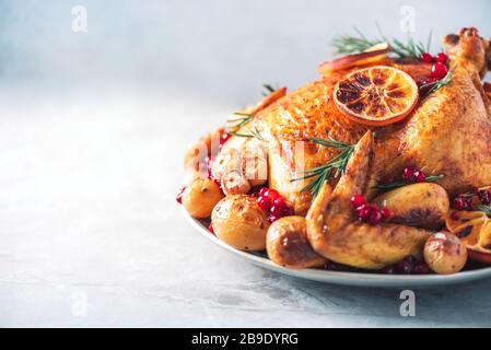 Roasted chicken with oranges, rosemary and cranberries on plate over concrete background. Traditional Thanksgiving or Friendsgiving holiday celebratio Stock Photo