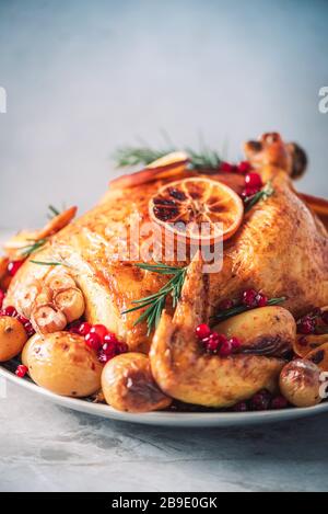 Roasted chicken with oranges, rosemary and cranberries on plate over concrete background. Traditional Thanksgiving or Friendsgiving holiday celebratio Stock Photo