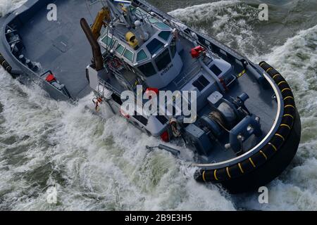 display of abilities of modern tugboat during the World Harbor days; tugboat going sideways making waves Stock Photo