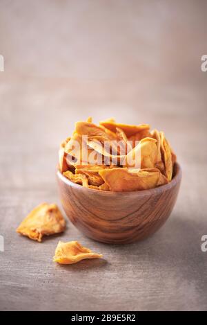 Dried mango in wooden bowl on wood textured background. Copy space. Superfood, vegan, vegetarian food concept. Macro of orange dried mango slices, sel Stock Photo
