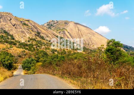 Road in foot of huge monolith rock called Sibebe next to Mbabane, capital city of Eswatini Stock Photo