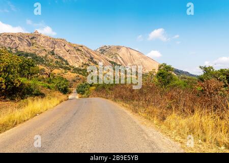 Road in foot of huge monolith rock called Sibebe next to Mbabane, capital city of Eswatini Stock Photo