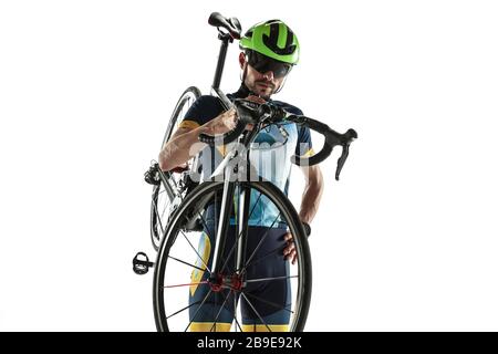 Triathlon male athlete cycle training isolated on white studio background. Caucasian fit triathlete practicing in cycling wearing sports equipment. Concept of healthy lifestyle, sport, action, motion. Stock Photo