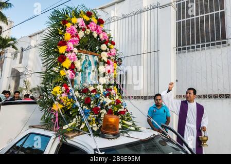 Priest blessing decorated taxis and drivers before the procession, Festival of Our Lady of Guadalupe, street in Catemaco, Veracruz state, Mexico Stock Photo