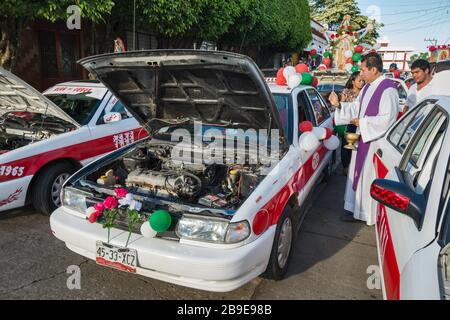 Priest blessing decorated taxis and drivers before the procession, Festival of Our Lady of Guadalupe, street in Catemaco, Veracruz state, Mexico Stock Photo