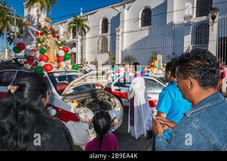 Priest blessing decorated taxis and drivers before the procession, Festival of Our Lady of Guadalupe, street in Catemaco, Veracruz state, Mexico Stock Photo