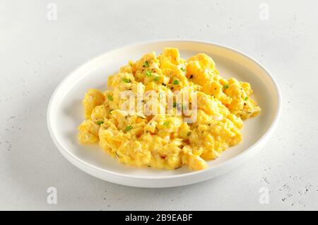 Scrambled eggs on plate over white stone background, close up view Stock Photo