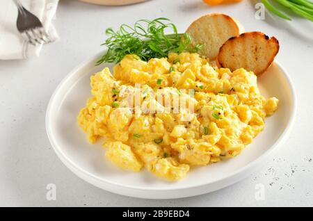 Scrambled eggs on plate over light stone background, close up Stock Photo