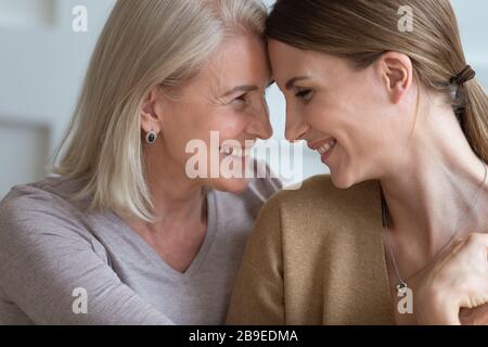 Happy older mother and adult daughter touching foreheads, feeling love Stock Photo