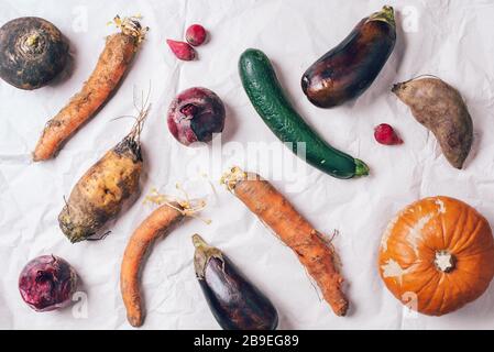 Ugly organic rotten vegetables with mutations on craft paper background. Concept of zero waste production. Copy space. Spoiled non gmo vegetables with Stock Photo