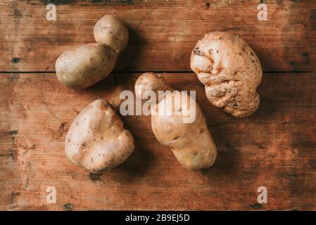 Ugly potatoes on wooden background. Ugly, unnormal vegetable, zero waste and plastic free concept. Top view. Copy space Stock Photo