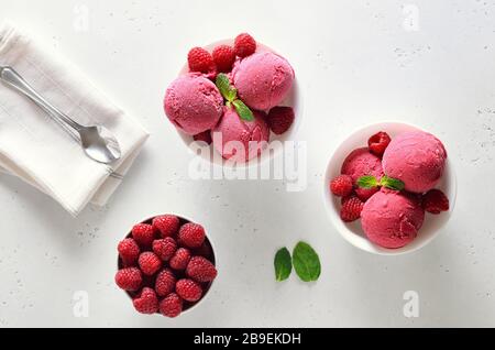 Raspberry ice cream scoop with fresh raspberries in bowl and fresh raspberries over white stone background with free text space. Top view, flat lay Stock Photo