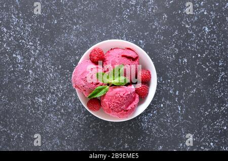 Raspberry ice cream scoop with fresh raspberries in bowl on stone background with copy space. Cold summer dessert. Top view, flat lay Stock Photo