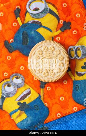 Golden Oreo biscuit on serviette with Minions - Minions juggling with Golden Oreo biscuit, sandwich biscuits with a vanilla flavour filling Stock Photo